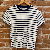 Striped t-shirt on a wooden hanger against a brick wall