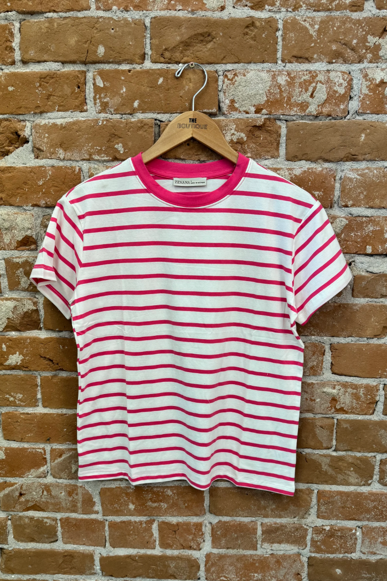 Pink and white striped t-shirt on a wooden hanger against a brick wall.