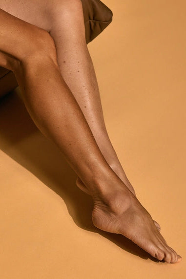 Close-up of a person's legs with sheer tights on a beige background