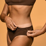 Person wearing a brown bikini against an orange background