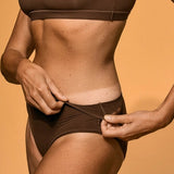 Person wearing a brown bikini against an orange background