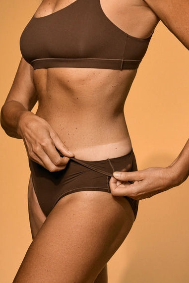 Person wearing a brown bikini against an orange background