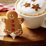 White mug with a festive drink and gingerbread cookies on a wooden surface