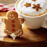 White mug with a festive drink and gingerbread cookies on a wooden surface