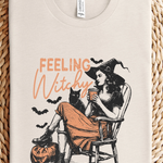 Beige t-shirt with 'Feeling Witchy' graphic design on a woven surface