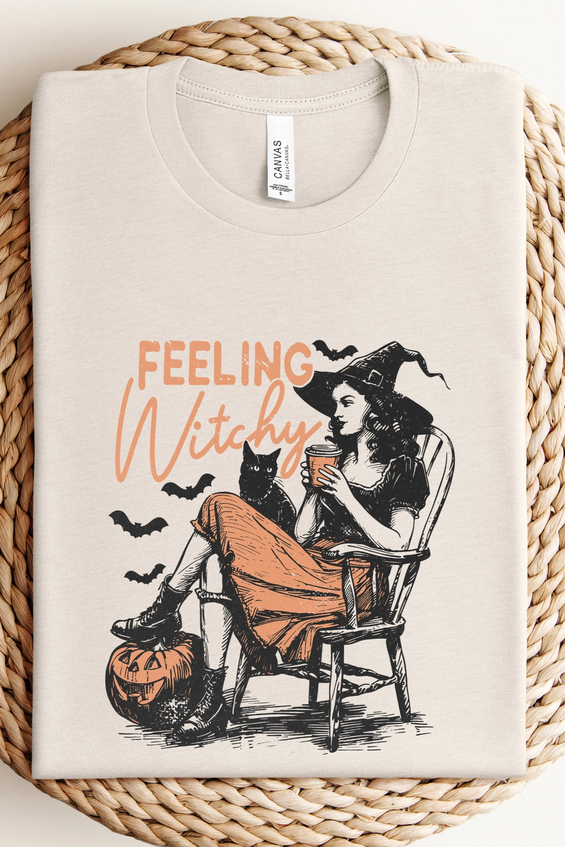 Beige t-shirt with 'Feeling Witchy' graphic design on a woven surface