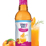 Skinny Mixes peach syrup bottle with a glass of peach juice and peaches on a white background