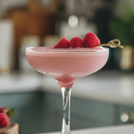 Pink cocktail with raspberries in a glass on a kitchen counter