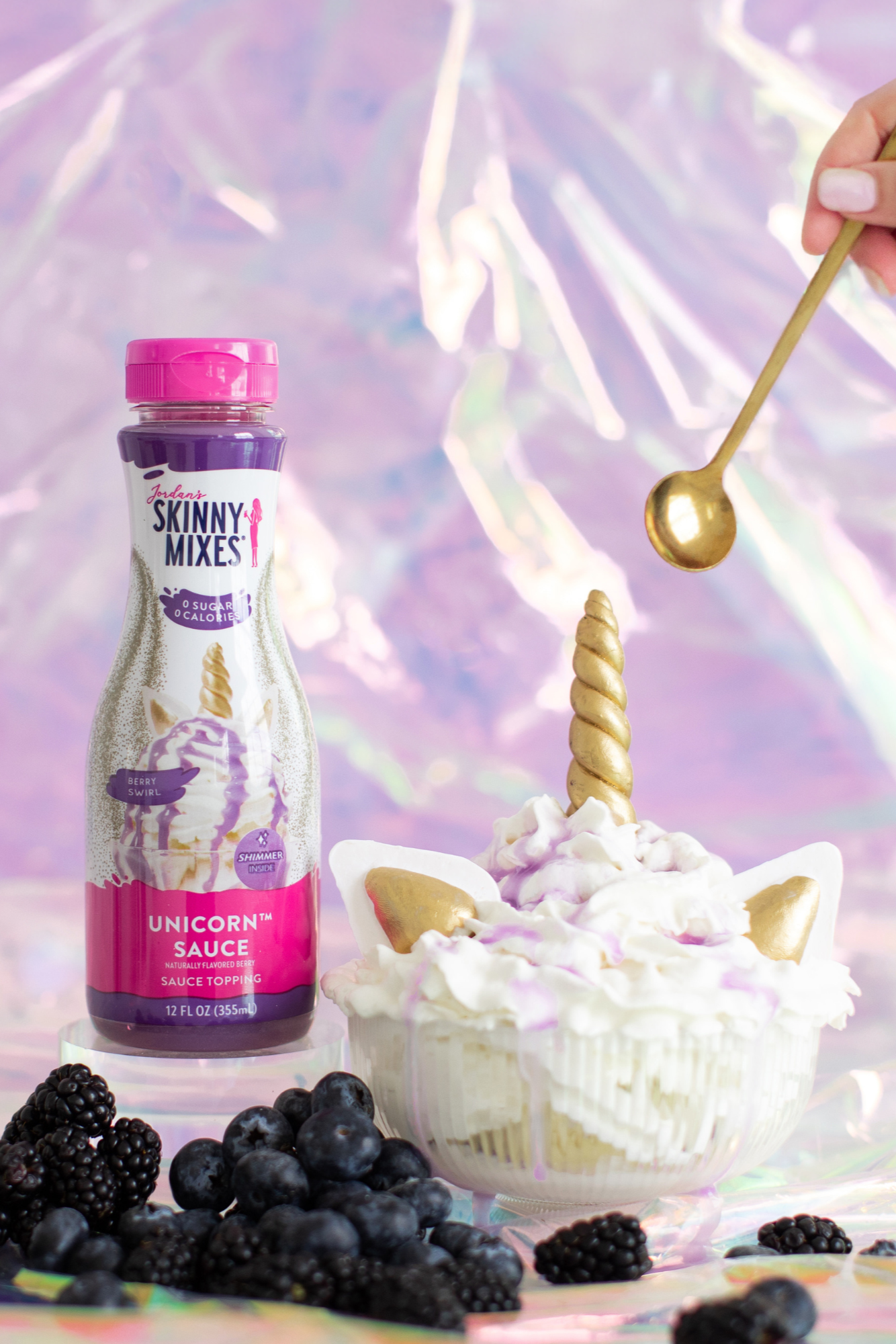 Skinny Mixes Unicorn Sauce bottle with a dessert and blackberries on a colorful background