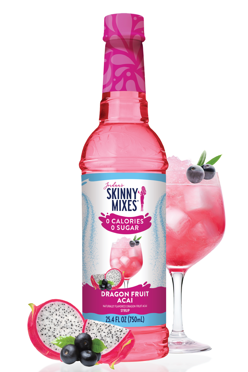 Skinny Mixes Dragon Fruit Acai syrup bottle with a glass of pink drink and dragon fruit slices on a white background