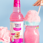 Bottle of Skinny Mixes Cotton Candy syrup with a pink cotton candy drink and cotton candy on a light blue background.