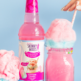 Bottle of Skinny Mixes Cotton Candy syrup with a pink cotton candy drink and cotton candy on a light blue background.