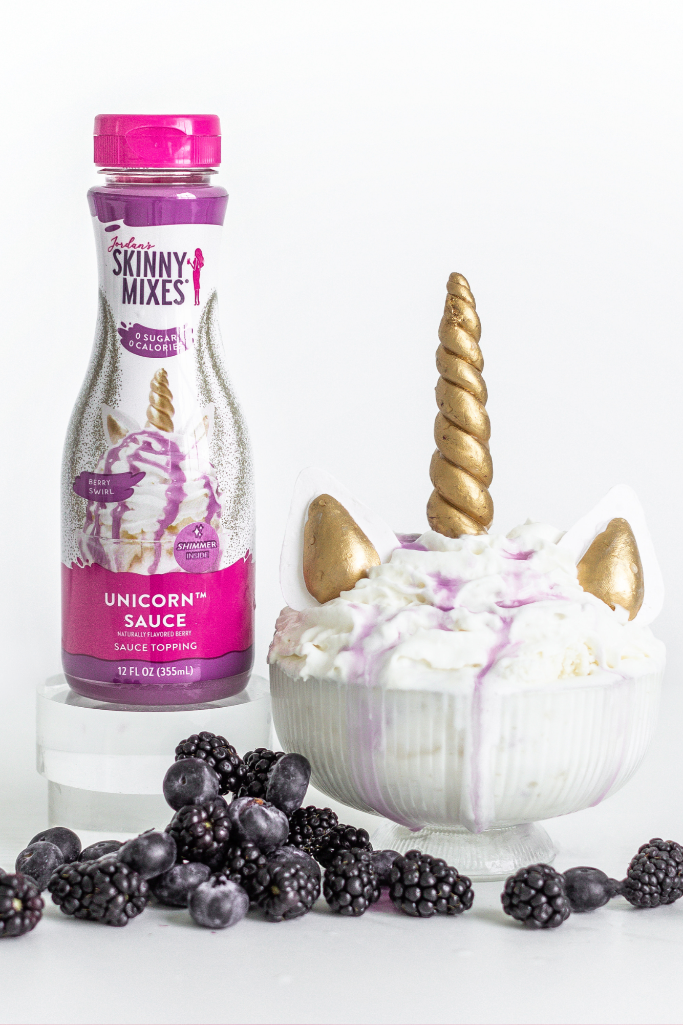 Unicorn-themed dessert with Skinny Mixes unicorn sauce bottle on a white background