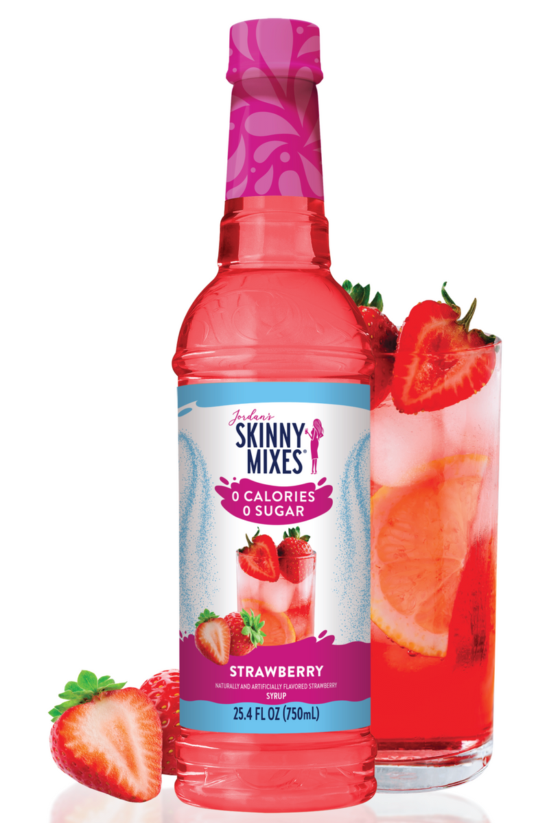 Bottle of Skinny Mixes strawberry syrup with a glass of strawberry drink and strawberries on a white background