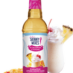 Bottle of Skinny Mixes Pineapple Upside Down Cake syrup with a glass of milkshake and pineapple slices on a white background