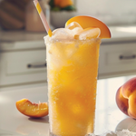 Peach-themed drink with ice and a peach slice on a kitchen counter