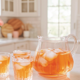 Clear pitcher and glasses of iced tea on a kitchen counter with lemons.