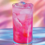 Glass of pink drink with ice cubes on a colorful background